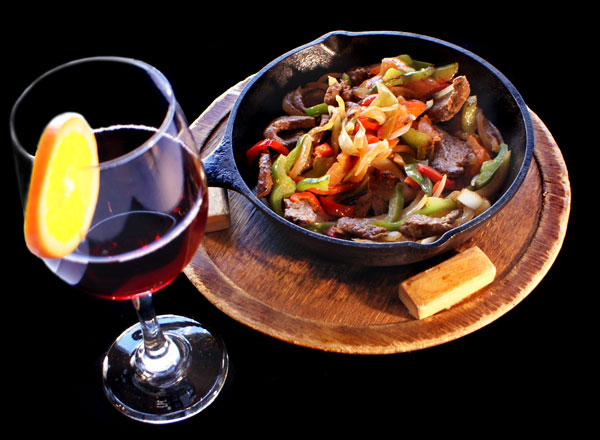 Sizzling fajita skillet with a glass of red wine